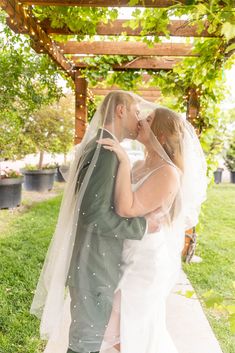 a bride and groom kissing under an arbor