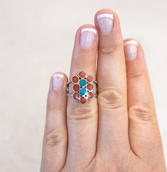 This is a vintage Native American made Sterling Silver Red Coral and Turquoise Dishta Statement ring.  Size: 6.25 Measurement: 3/4 inch long x 1/2 inch wide x 5mm in height Total Weight: 7 grams This features round sections of red coral with two round sections of turquoise at the center of the design. The use of this round sections of stone is a hallmark of the Dishta family designs, however this ring is not signed. The ring band also features a beautiful design with repeating cut out circles which adds a nice artisan touch to the ring. The ring was acid tested as sterling silver but it is not hallmarked. There is some patina on the inside of the ring but is in good vintage condition. - - - - - - - - - - - - - - - - - - - - - - - - -  Vintage Native American Rings: https://etsy.me/3AMZJK3 Native American Necklace, Native American Earrings, Native American Rings, Southwestern Jewelry, Red Band, Red Coral, American Made, Silver Fashion, Statement Rings