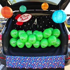 there are many green balls in the trunk of a car that is decorated with paper lanterns