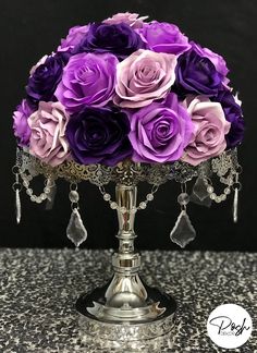 purple and pink roses are on top of a silver stand with crystal beaded chains