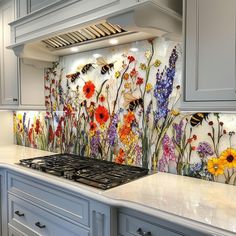 a kitchen with flowers painted on the backsplash and an oven hood in front of it