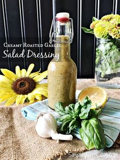 a bottle filled with salad dressing sitting on top of a table next to sunflowers