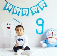 a baby sitting on top of a bed in front of a banner with the number nine