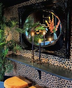 candles are lit in front of a mirror on a shelf with leopard print wallpaper