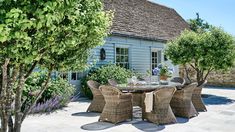 an outdoor table and chairs in front of a house