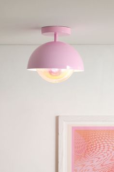 a pink light hanging from the ceiling above a bed in a room with white walls