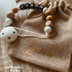 a wooden beaded bracelet with the name mason on it next to a drawstring bag