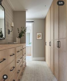 an empty hallway leading to a bedroom with large wooden cabinets and drawers on both sides