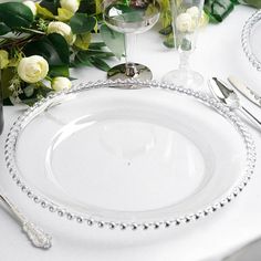 the table is set with white roses and silverware for an elegant dinner party or special occasion