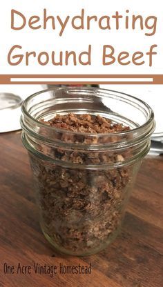 a glass jar filled with ground beef on top of a wooden table