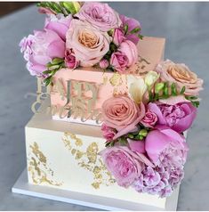 a pink and gold wedding cake with flowers on top