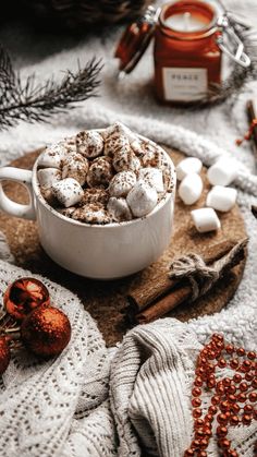 hot chocolate and marshmallows in a white bowl on a wooden tray surrounded by christmas decorations