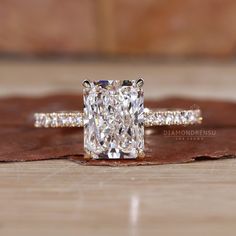 a cushion cut diamond ring sitting on top of a wooden table