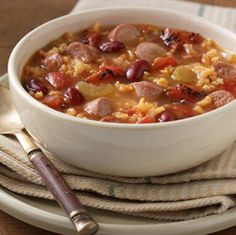 a white bowl filled with beans and corn on top of a plate next to a fork