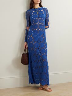 a woman standing in front of a white wall wearing a blue dress with cut outs