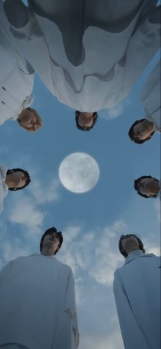 four people are standing in the middle of a circle looking up at the sky and clouds