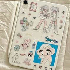 an ipad with stickers on it sitting on top of a white sheet covered surface