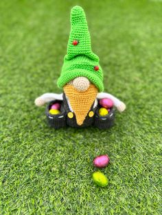 a small knitted gnome sitting on top of green grass