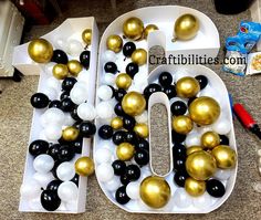 the number ten is made out of balloons and black and white balls with gold accents