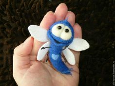 a hand holding a small blue and white stuffed animal with wings on it's fingers