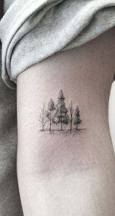 a small tree tattoo on the right side of the thigh, with trees in the background