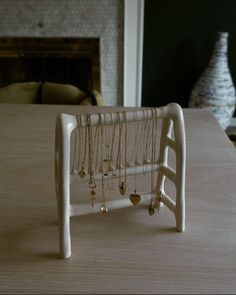 a jewelry rack with necklaces hanging from it on a table next to a fireplace