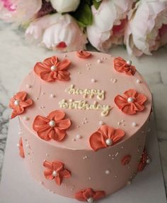 a pink birthday cake with flowers on it