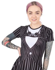 a woman with pink hair wearing a black and white striped dress, tattoos on her arm