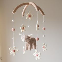 a crocheted unicorn mobile with flowers hanging from it's sides and a wooden stick in the middle