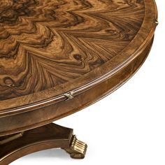 a round wooden table with an intricate design on it's center piece and gold trim around the edges