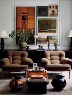 a living room with two couches and some chairs in front of paintings on the wall