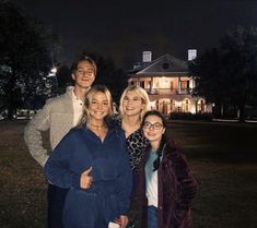 a group of people standing in front of a house at night with the lights on