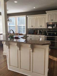 a large kitchen with an island in the middle and white cabinets on either side of it