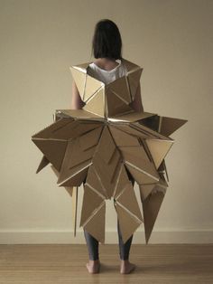 a woman standing in front of a wall made out of cardboard boxes with the shape of an origami star