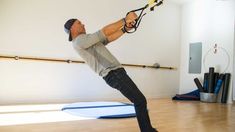 a man holding onto a rope while standing on top of a surfboard in a room