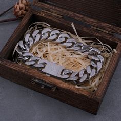 a wooden box filled with lots of silver bracelets on top of a gray floor