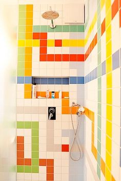 a bathroom with colorful tiles on the wall and shower head mounted to the side of the bathtub