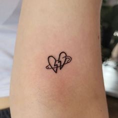 a small tattoo on the arm of a woman with two hearts and an arrow in the middle