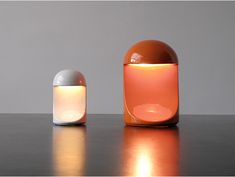 an orange and white lamp sitting on top of a table next to another light bulb