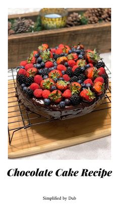 a chocolate cake with berries and strawberries on top is sitting on a cooling rack