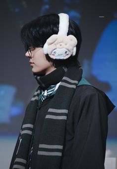 a man with black hair wearing a scarf and ear muffs on top of his head