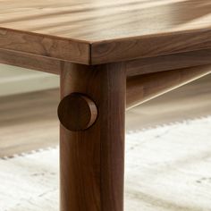 a close up of a wooden table with a white rug on the floor behind it