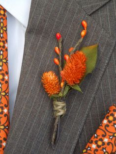 a boutonniere with orange flowers is tied to a suit jacket and tie