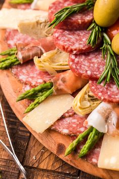 a pizza topped with meat, cheese and asparagus on a wooden cutting board