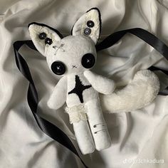 a white stuffed animal laying on top of a black ribbon