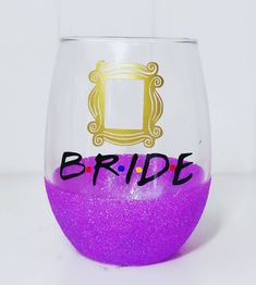 a purple wine glass with the word bride painted on it and a gold framed frame