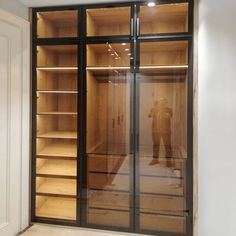 an empty walk in closet with glass doors and shelves on both sides, two people standing inside