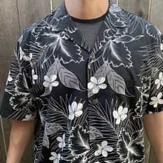 This medium worthy cotton shirt is in great vintage condition with almost no wear. Beautiful abstract pattern of hibiscus flowers and palm leaves in a crisp black and white. One chests  pocket that perfectly aligns with the pattern and disappears into the shirt. Lovely coconut shell buttons. Well made of quality materials in Hawaii, USA. Size XL-Model size men’s Large-Approximate measurement when laid flat:25” armpit to armpit21” shoulder to shoulder 10.5” sleeve 31.5” back collar to hem Vintage Black Summer Shirt, Black Cotton Hawaiian Shirt For Beach, Black Camp Collar Shirt For Beach, Black Camp Collar Shirt For The Beach, Black Collared Camp Shirt For Vacation, Black Hawaiian Shirt With Camp Collar For Beach, Black Printed Hawaiian Shirt For Beach, Vintage Black Summer Camp Shirt, Printed Black Camp Shirt For Vacation