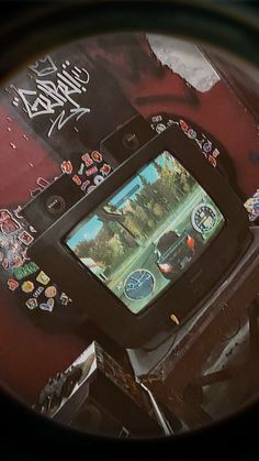 a close up of a cell phone with graffiti on the wall behind it and an image of a person playing video games