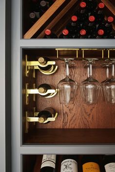 several wine glasses and bottles in a wooden shelf